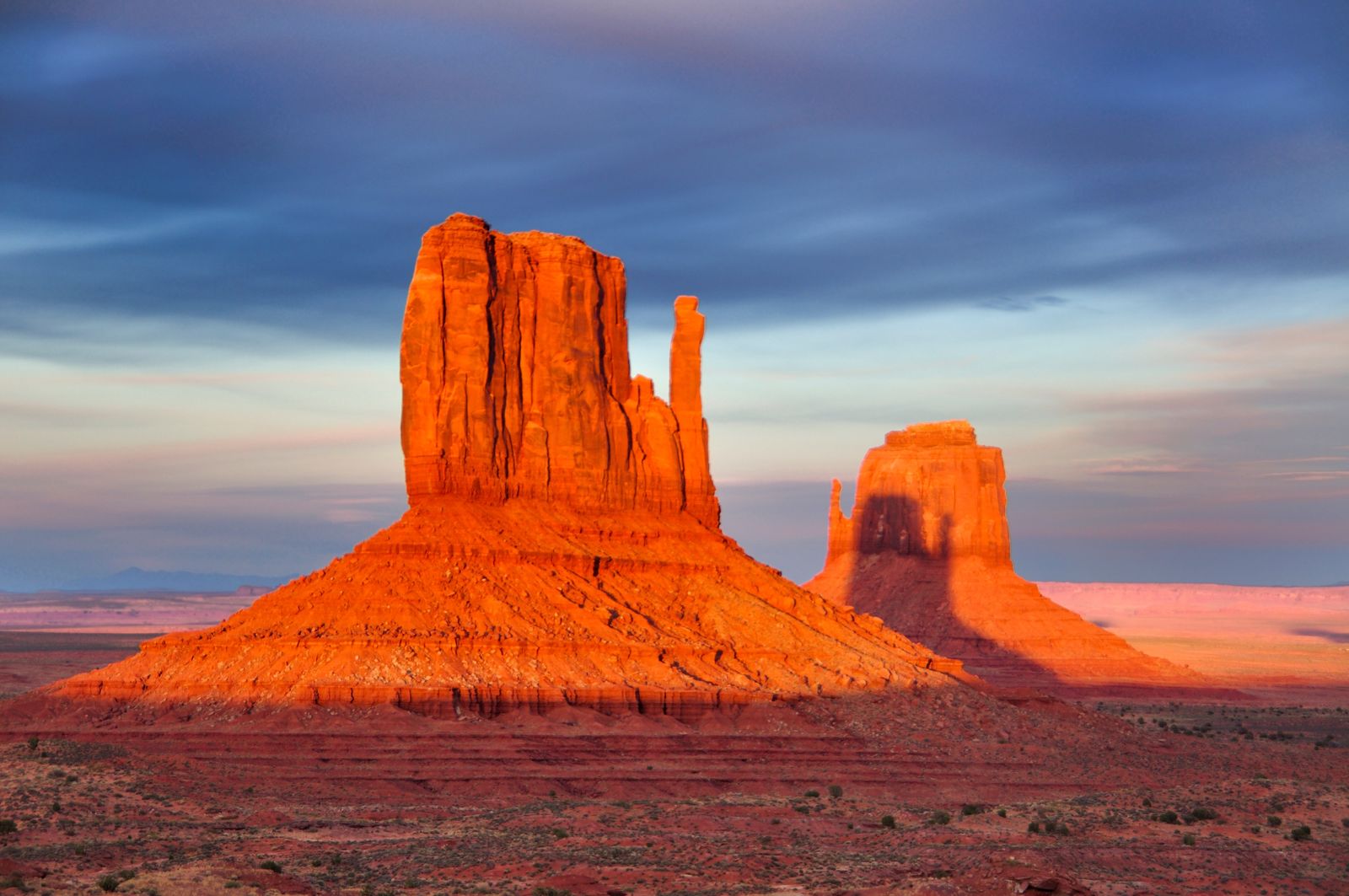 The Mitten buttes glowing red in low sunlight above the desert